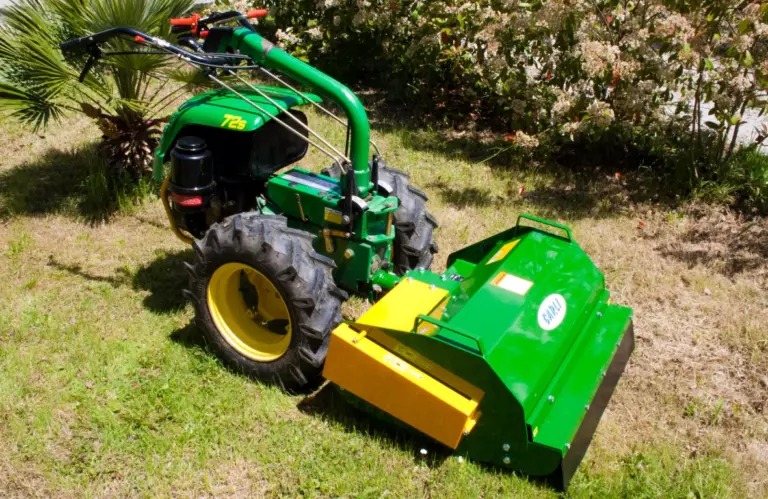 La trincia montata su un motocoltivatore verde, su un prato al sole, vista dal lato del carter giallo.